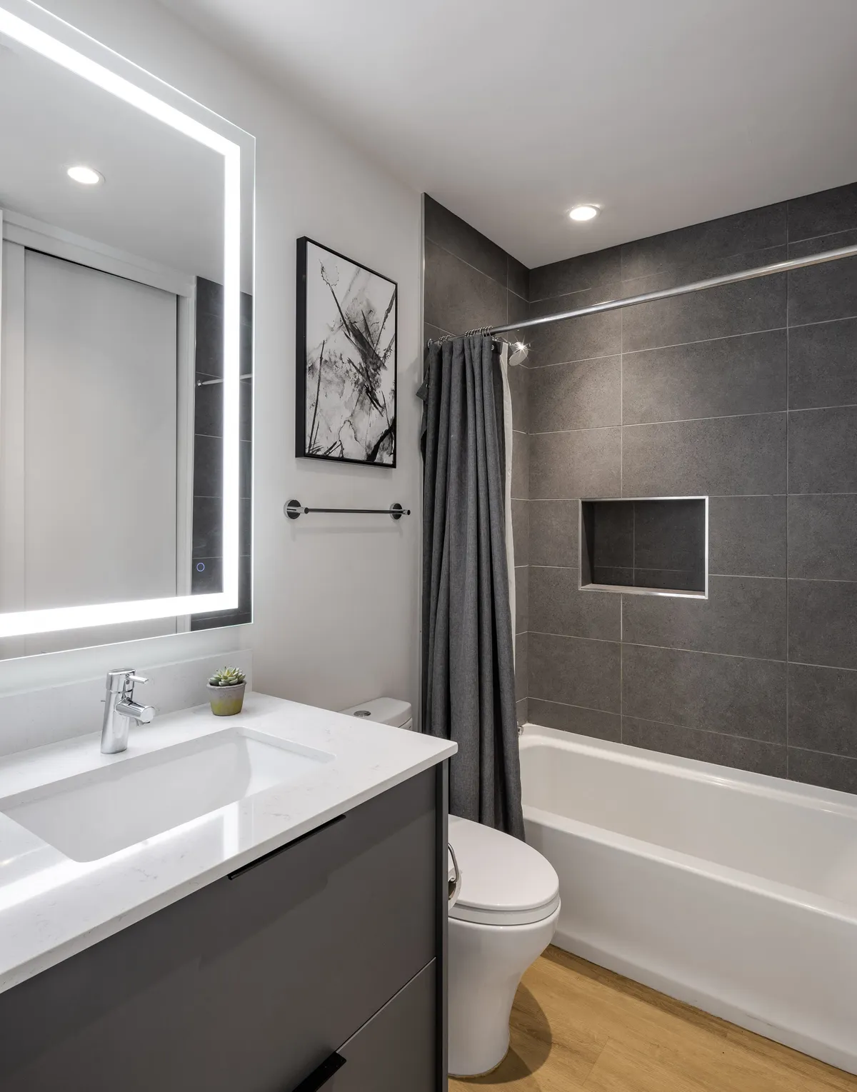 A modern bathroom with a vanity and sink, framed artwork, and a sleek bathtub. The overall vibe is serene and contemporary, offering an inviting space for both morning preparations and evening relaxation.