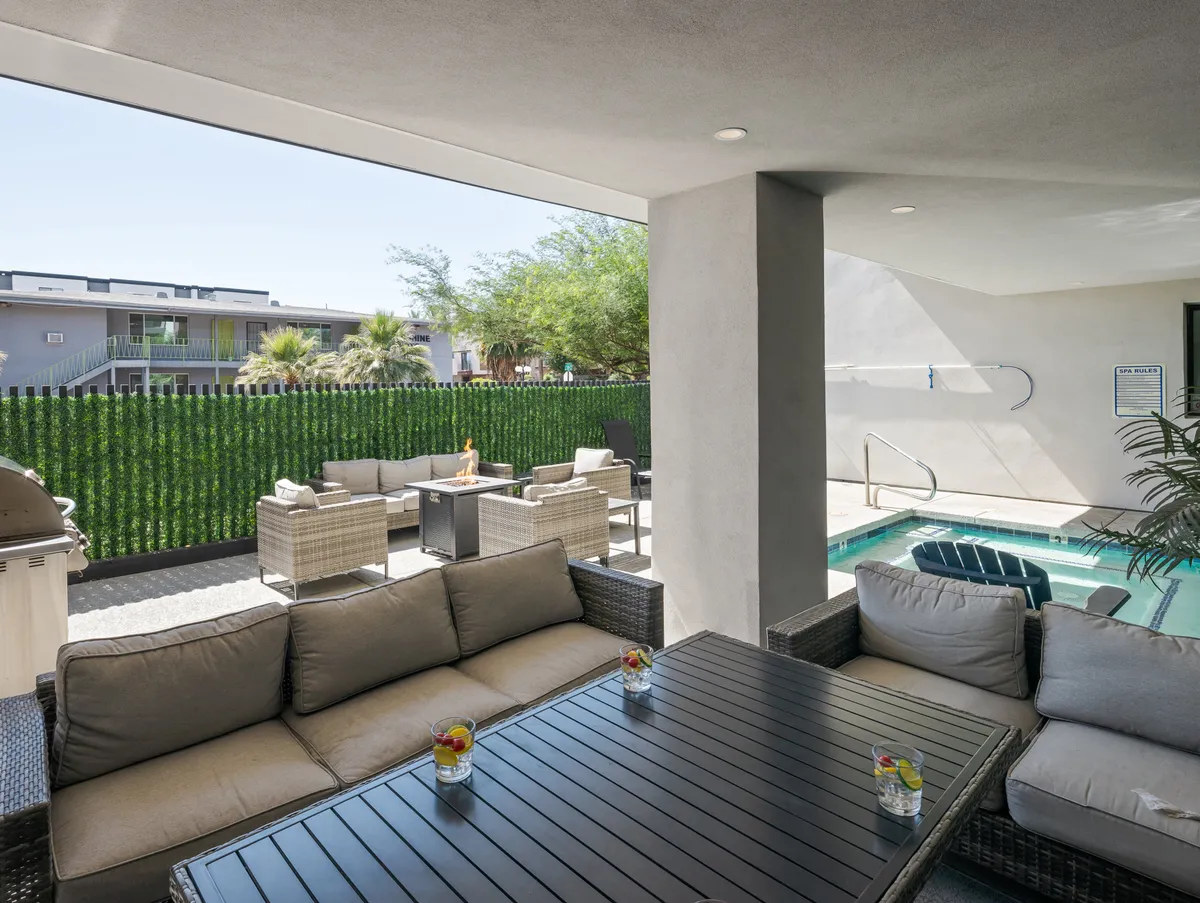 A stylish outdoor seating area by a swimming pool, bordered by a green privacy wall. The space is set up for groups to relax and socialize, with comfortable seating perfect for evening gatherings or unwinding after a night out in Old Town.
